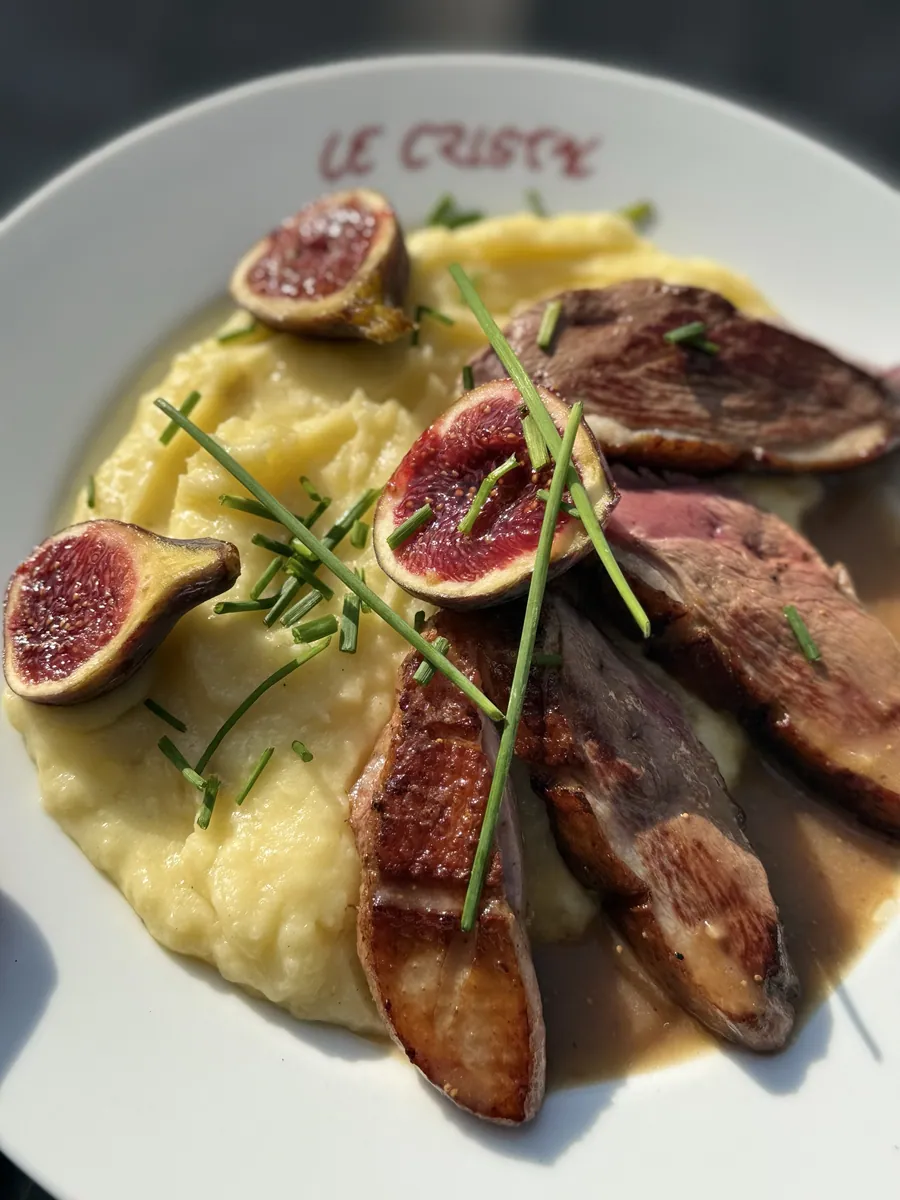 Magret de canard aux figues servi dans une assiette siglée Le Cristal